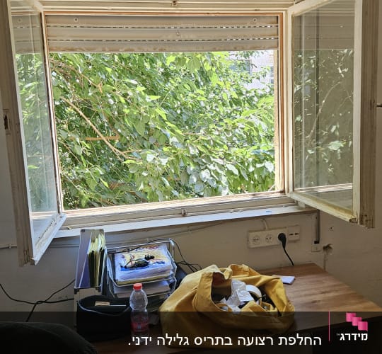 חלון פתוח עם תריסים, שולחן עם חפצים שונים